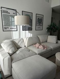 a living room with white furniture and pictures on the wall