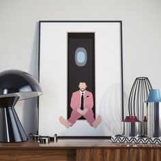 a man in a pink suit sitting on the floor next to a lamp and table