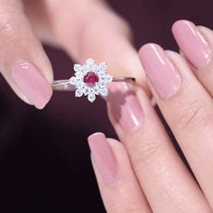 a woman's hand holding a diamond and ruby ring