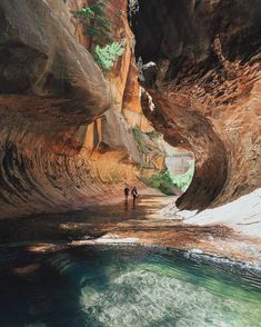 two people are walking through a narrow canyon