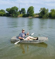 a man sitting on top of a kayak in the water holding a paddle with both hands