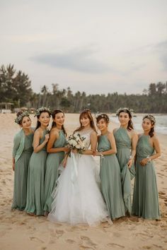 a group of women standing next to each other on top of a sand covered beach