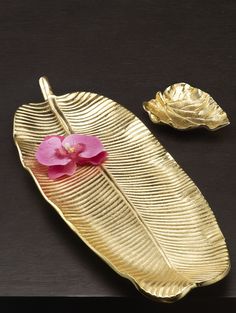 a gold plate with a pink flower on it and two other items next to it