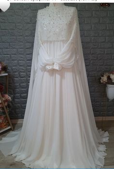 a wedding dress on display in front of a brick wall