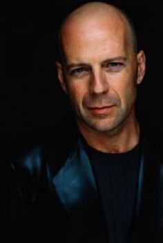 a bald man in a black jacket looking at the camera