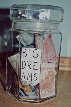 a glass jar filled with lots of different types of paper and magnets on top of a wooden table