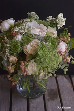 a vase filled with lots of flowers on top of a wooden table