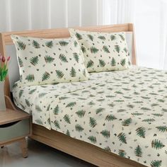 a bed with white sheets and green trees on it