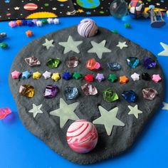 a rock with stars and planets on it sitting on a blue surface next to other rocks