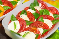 tomatoes and mozzarella with basil leaves in two white bowls on a colorful tablecloth