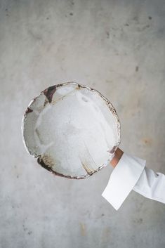 a person's hand holding a white plate with dirt on it