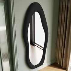 a mirror mounted to the side of a wall next to a window in a room