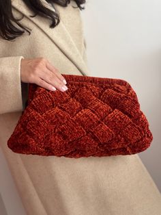 a woman is holding an orange purse in her hand