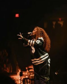 a woman singing into a microphone on stage