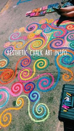 someone is drawing on the ground with chalk and crayon pencils in front of them