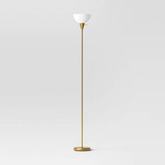 the floor lamp is gold and has a white shade on it's top half