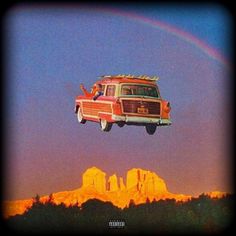 a van is flying over the water with a rainbow in the sky and mountains behind it