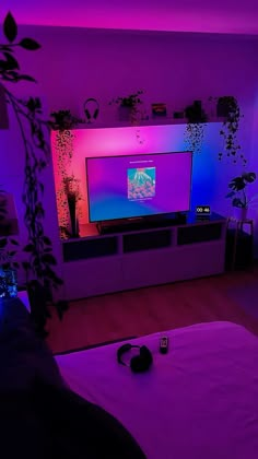 a living room with purple lighting and a flat screen tv on the wall in front of it