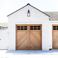 two wooden garage doors in front of a white brick building