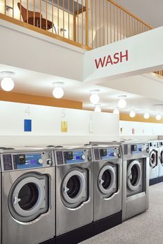 wash machines lined up in a large laundry room with the word wash on it's sign above them