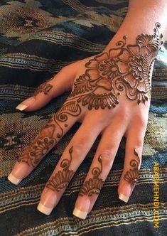 a woman's hand with henna tattoos on it, showing the intricate design