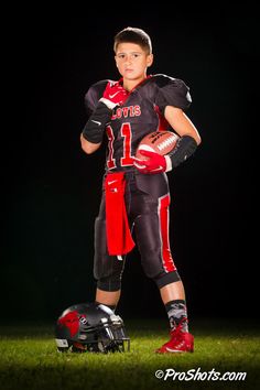 a young boy wearing a football uniform and holding a ball