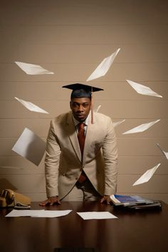 a man in a suit and tie standing at a desk with papers flying around him