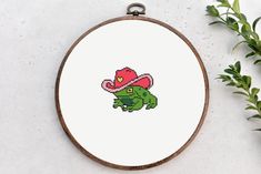 a cross stitch pattern with a green dinosaur wearing a pink hat