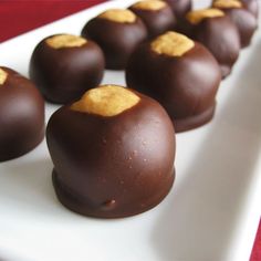 there are chocolates with peanut butter on them sitting on a white plate, ready to be eaten