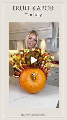 a woman holding a fake turkey made out of candy sticks and apples with the words fruit kabob turkey on it