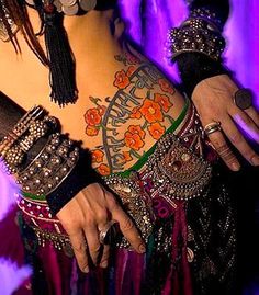 a woman with lots of tattoos on her arm and chest, wearing some bracelets