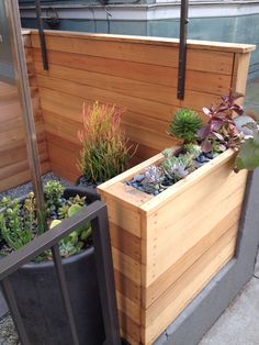 a wooden planter filled with lots of succulents next to a building