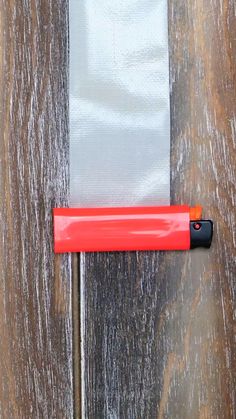 an orange piece of plastic sitting on top of a wooden floor next to a metal pole