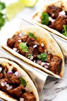 three tacos with meat, onions and cilantro