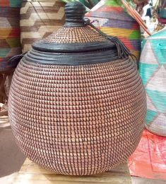 woven baskets are stacked on top of each other in different colors and sizes, including one with a black lid