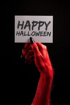 a hand holding up a sign with the words happy halloween written in black on it