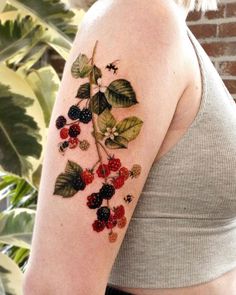 a woman's arm with berries and leaves tattooed on the side of her shoulder