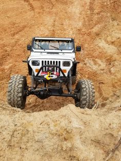 a white jeep driving on top of a dirt covered hill in the middle of nowhere