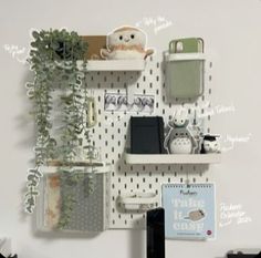 a white wall with some shelves and plants on it's side next to a laptop