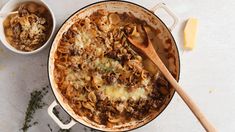 a pot filled with pasta and meat next to a bowl of grated parmesan cheese