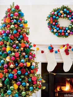 christmas tree decorated with colorful balls and pom - poms in front of fireplace