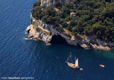 an aerial view of two boats in the water next to a cliff with trees on it