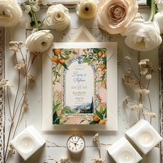 a wedding card with flowers and candles on the table next to it is surrounded by white roses