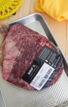 a piece of raw meat sitting on top of a metal tray next to a yellow object