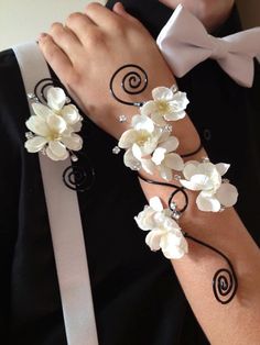 two people wearing matching wristbands with white flowers on their arm and one has a bow tie