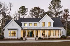 a large white house with lots of windows on the front and side of it at night