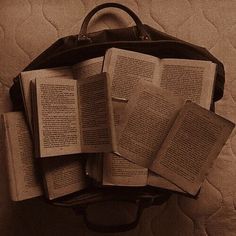 an open suitcase sitting on top of a bed filled with lots of book's