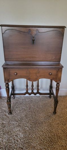 an old wooden desk sitting on top of a carpeted floor