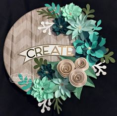 a wooden sign with paper flowers and the word create on it's center piece