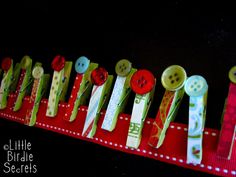 a row of different colored buttons sitting on top of a red ribbon covered table cloth